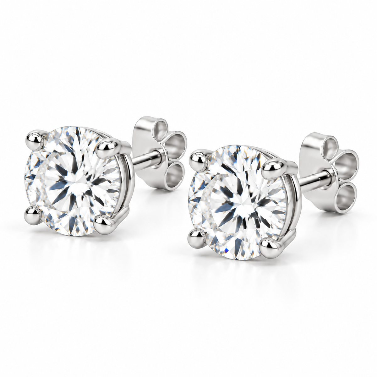 Angled view of lab-grown round diamond stud earrings in 14k white gold with four-prong settings and push backs